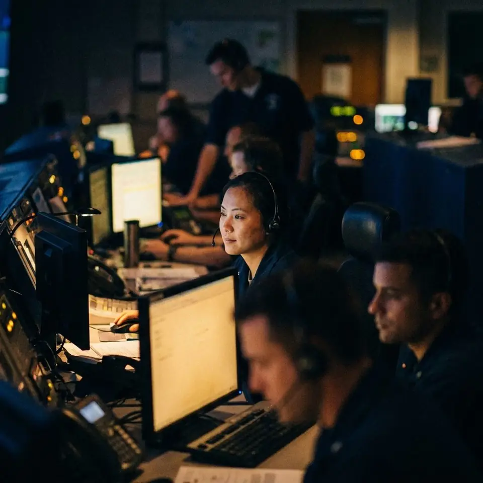 Call handlers wearing headsets in a dim control room